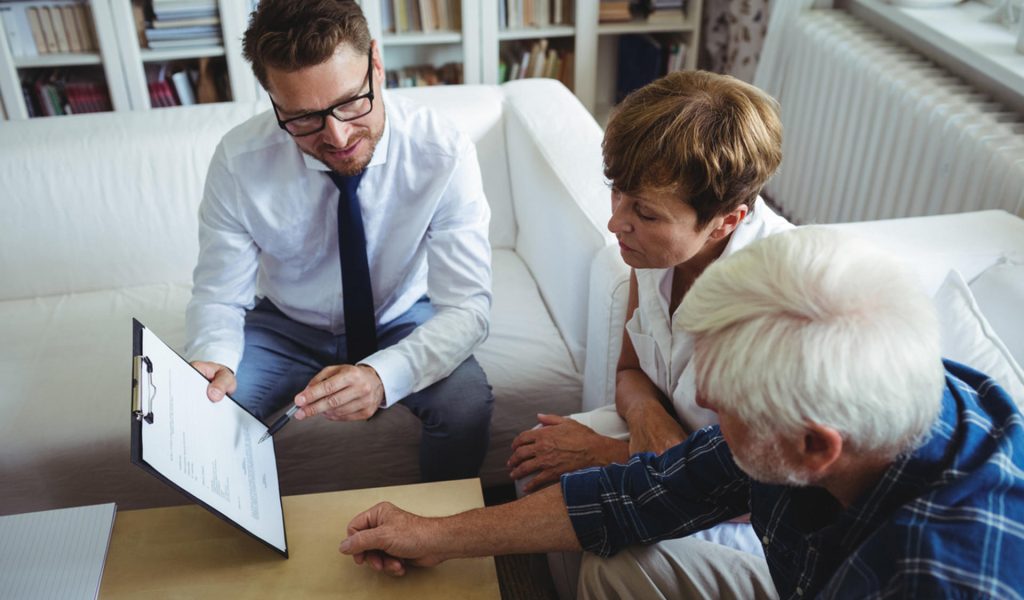 Senior couple planning their investments with financial advisor in living room